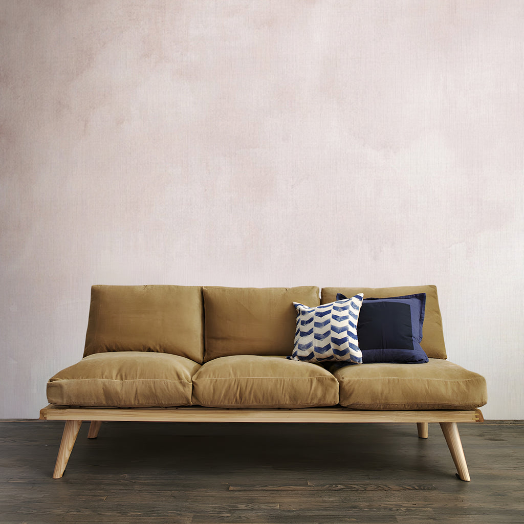 Aista, Ombre Watercolour Wallpaper  in blush pink  featured in a room with wooden sofa and brown cushion