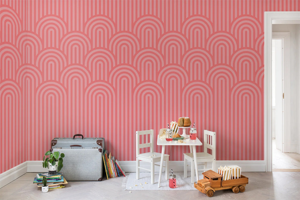 Arch Hills, Geometric Wallpaper in pink featured on a wall of a kid’s playroom with white mini table set surrounded by toys, and two grey briefcases