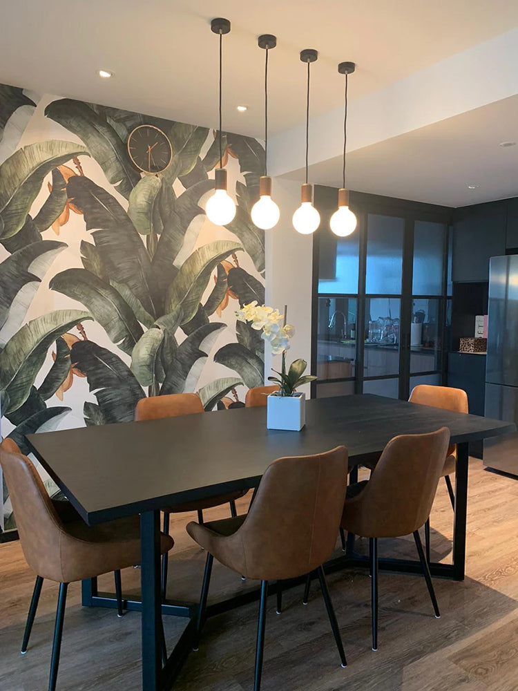 Banana Leaves, Tropical Pattern Wallpaper featured on a wall of a dining area with  black table, wooden chair and 4 pendant lights