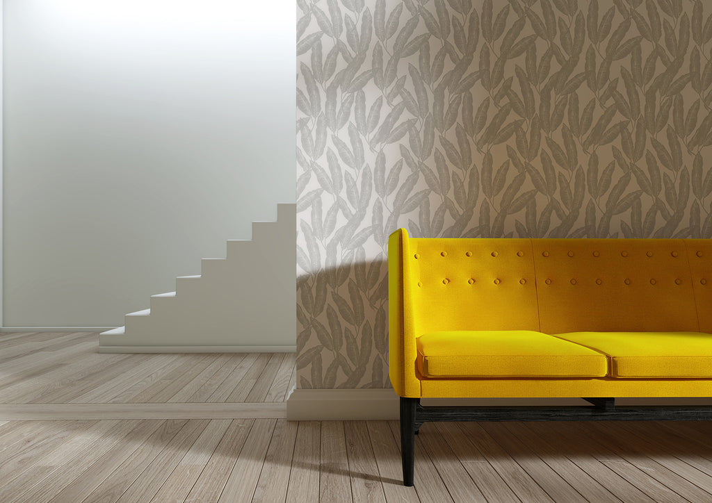 Botanist, Tropical Pattern Wallpaper in Light grey featured on a wall of a room, with yellow sofa on a wooden flooring, a part of a staircase can also be seen