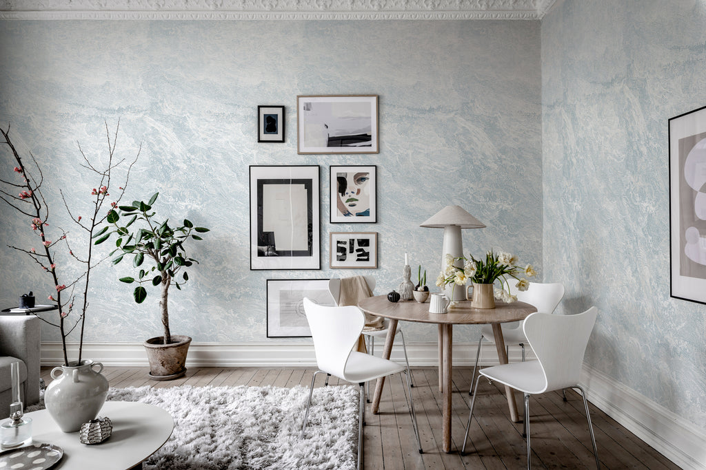 Breeze, Waves Mural Wallpaper in blue featured on the wall in a room with round table and chairs