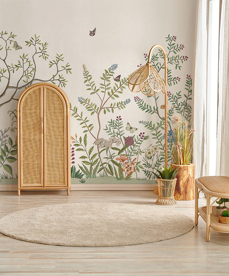 A tranquil room with Butterfly Garden wallpaper, featuring ratttan cupboard, lamp and stool, and potted plant on a light wooden floor, bathed in soft sunlight. The room exudes a serene ambiance, enhanced by natural elements and soft lighting. 