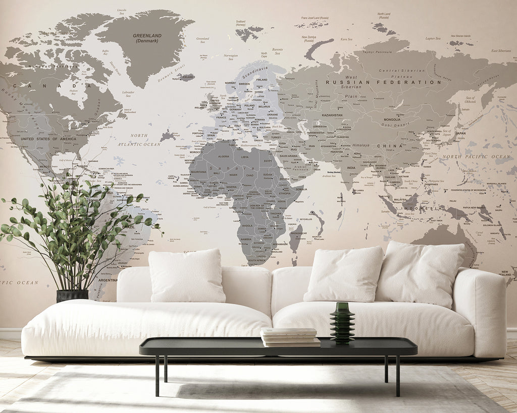 A modern, minimalist room featuring a large, comfortable white sofa. A sleek black coffee table sits in front, adorned with small green plants. The room’s ambiance is enhanced by the ‘Classic Atlas, World Map Mural Wallpaper’ on the wall behind the sofa.