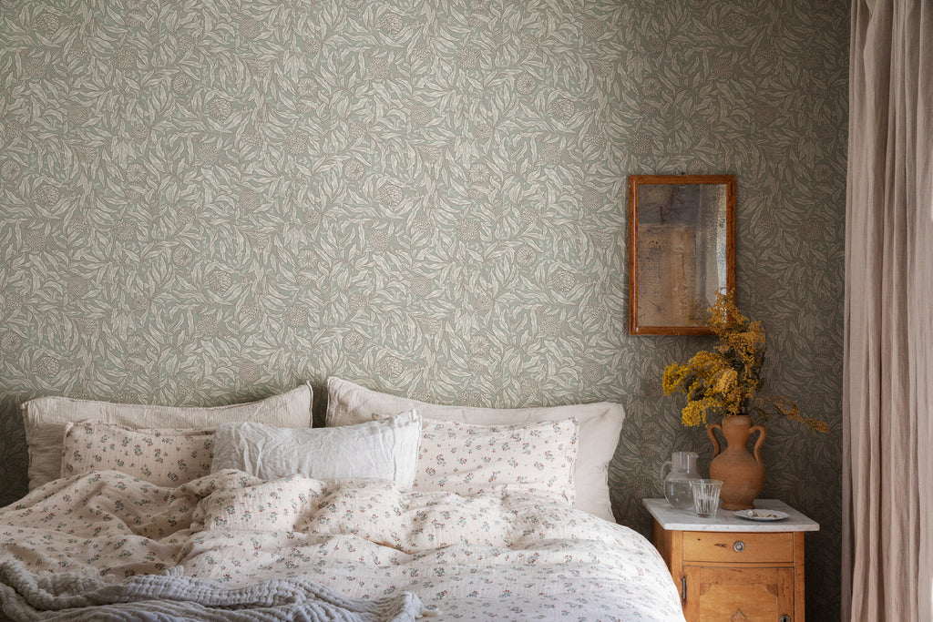 Olof, Floral Pattern Wallpaper in Green  featured on a wall of a bedroom with a bed with a wooden side table with flower on it. 