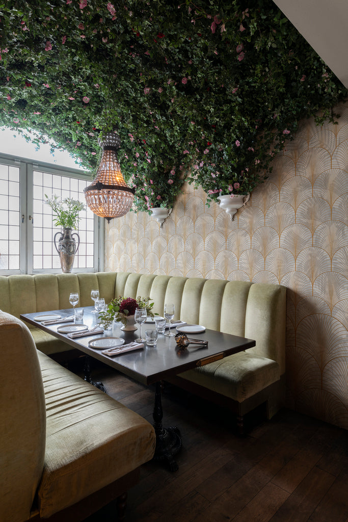 Palm Gold Arch, Pattern Wallpaper featured on a wall of a restaurant with brown table and plants on the ceiling