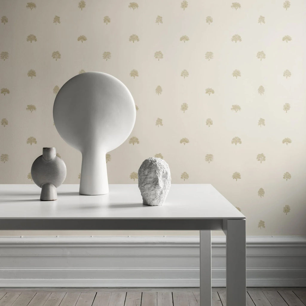 Rowena Trees Patterned Wallpaper in blush pink featured on a wall of a room with a white table and white furniture on top