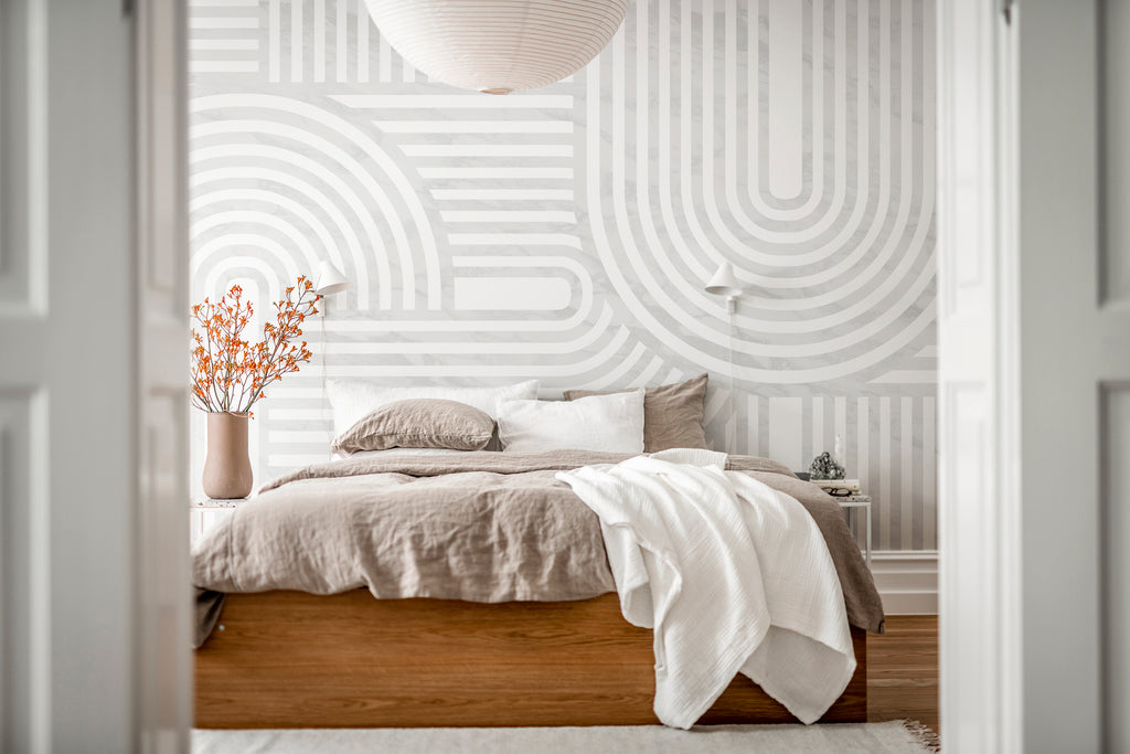 Stella Arch, Geometric Mural Wallpaper in grey featured on the wall of a bedroom with soft fabrics
