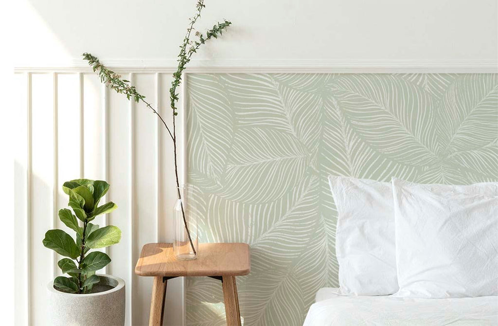 Noelle Fern, Tropical Pattern Wallpaper, in green as seen in a cozy living area with comfortable chair and soft pillows. 
