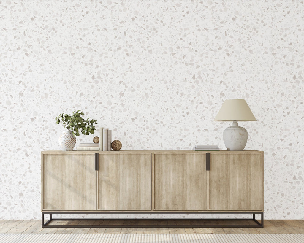Terrazzo Blanc, Faux Texture Wallpaper accents a wall alongside a wooden console table cabinet and wood flooring.