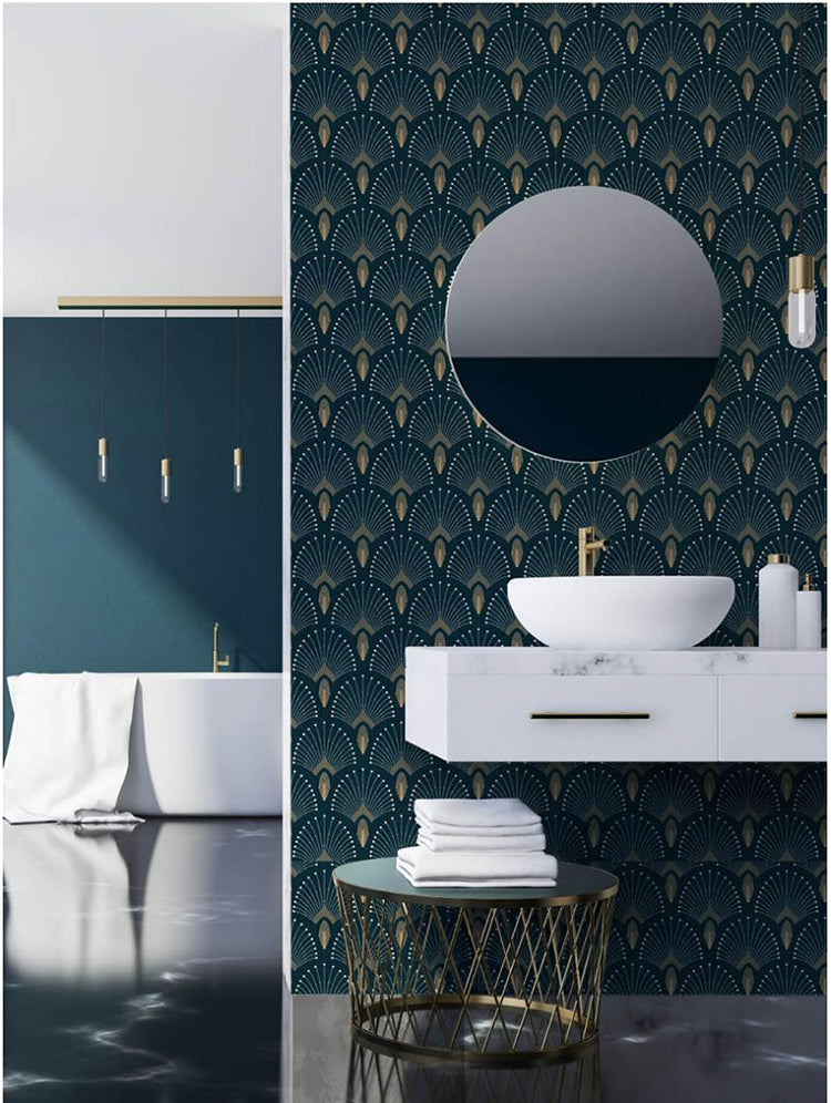 A modern bathroom with a white basin on a floating vanity, round mirror, gold faucet, and a visible tub. The room is illuminated by three hanging lights above the tub. The elegance of the room is enhanced by the 1920s Fan, Geometric Wallpaper in Dark Blue.