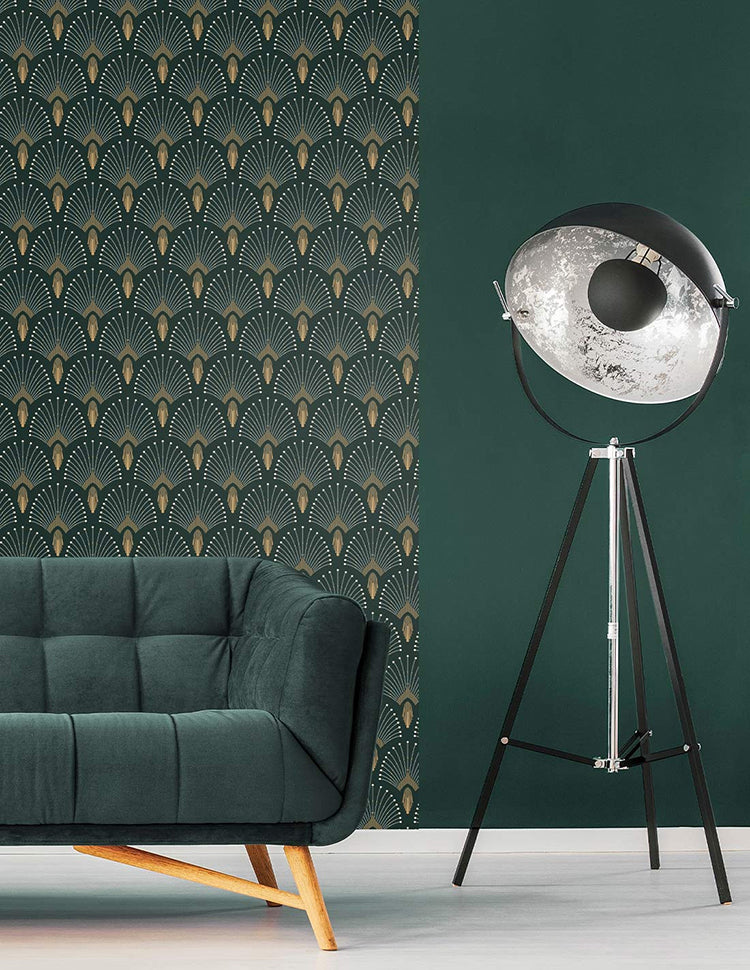 An elegant room with a plush dark green sofa and a unique silver studio light on a tripod. The room is accentuated by the 1920s Fan, Geometric Wallpaper in Dark Green, adding a touch of sophistication.