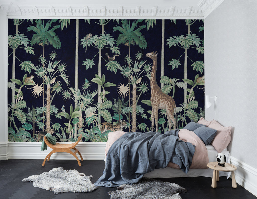 A Walk in the Jungle, Mural Wallpaper in dark blue featured on a wall a bedroom against a bed with pink and blue bedsheet and a wooden chair on the side.