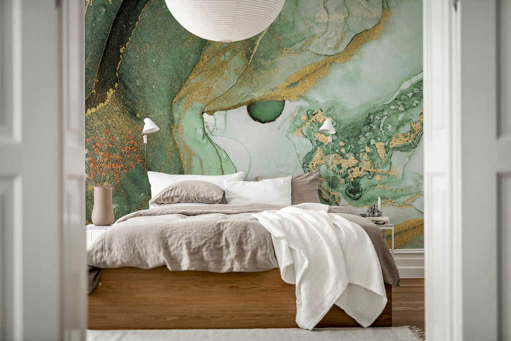 Agate Crystal Marble Texture Wallpaper in Green featured on the wall of a bedroom, with a bed that has wood framing, in dirty white bedsheet, white pillows and a white throw blanket. 