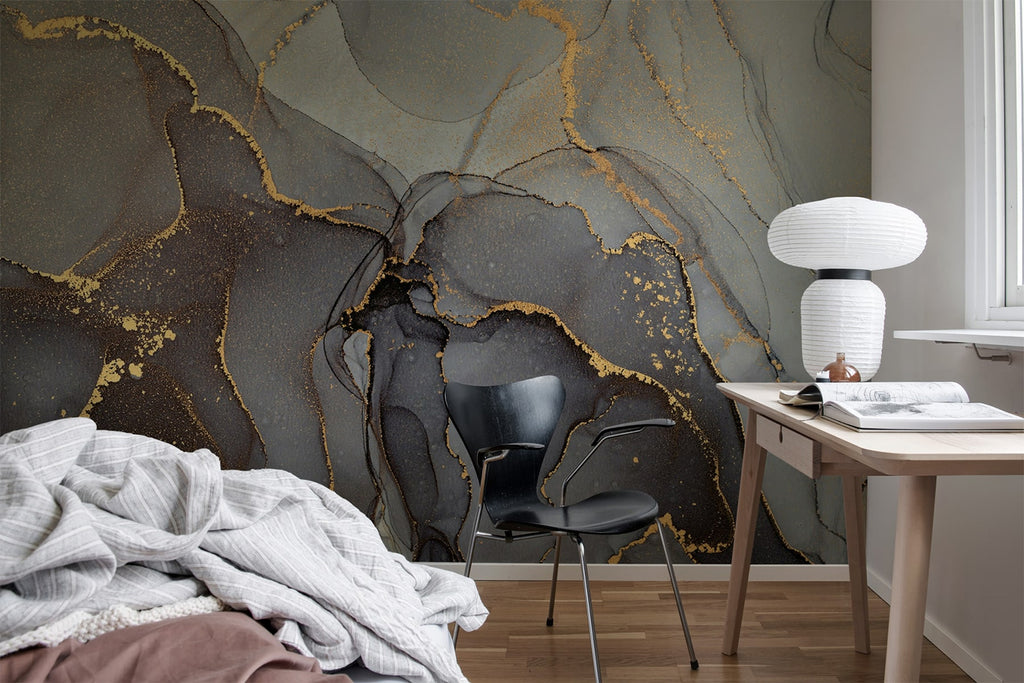 Agate Crystal Marble Texture Wallpaper in Onyx Black featured on a wall of a bedroom with a part of the bed seen, along with a wooden study table that has a book and a lamp, and a black chair. 