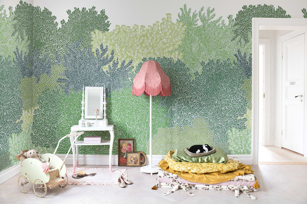Alice Garden, Mural Wallpaper in green featured in a kid’s playroom with a pink lamp and several scattered toys and fabric