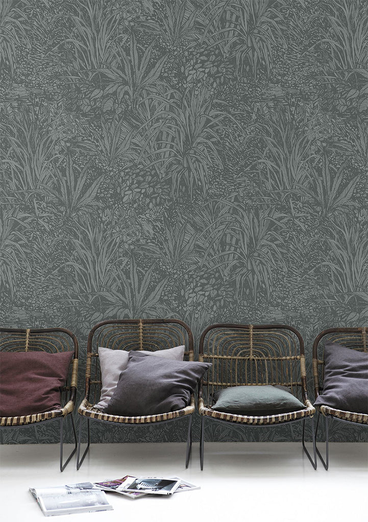 Amazon, Botanical Pattern Wallpaper  in Stratos Grey featured in a room with rattan chairs, pillows and magazines on the ground