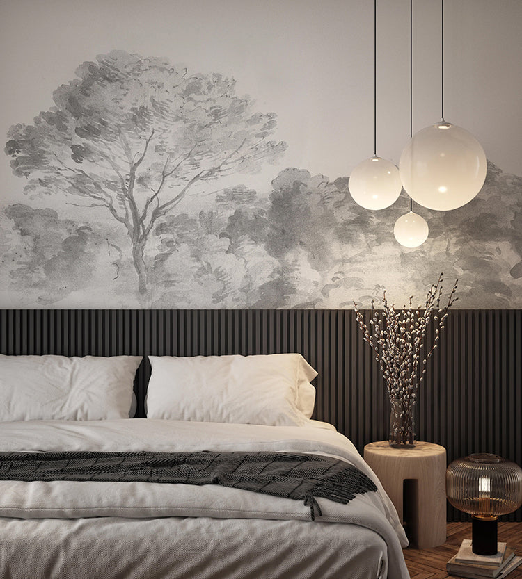 A modern bedroom with a plush bed, white bedding, and a grey throw blanket. A wooden side table holds a vase with branches. Pendant lights and An Old World Arboretum’ watercolour mural adds a contemporary touch. 