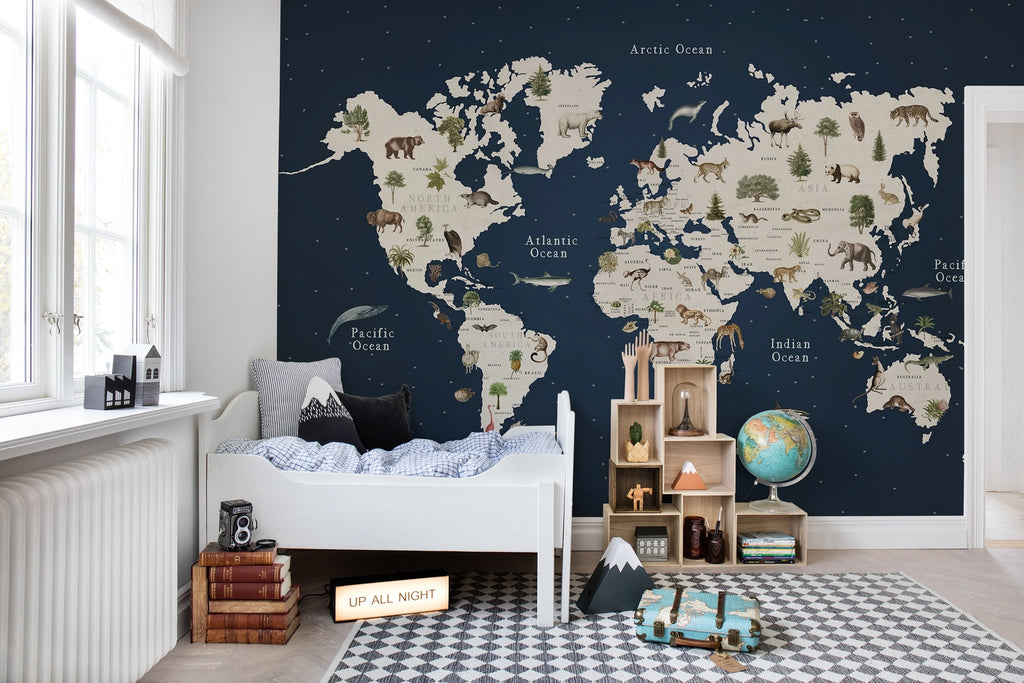 Animal World, World Map Mural Wallpaper dark blue featured on a children's bedroom with a bed in a wooden frame, stacked books, suitcase and toys lying on the ground.