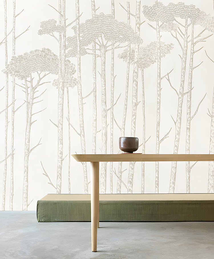 Ara’s Birch Trees, Mural Wallpaper in Sand, adorns a room featuring a wooden table with a ceramic cup and a green bench.