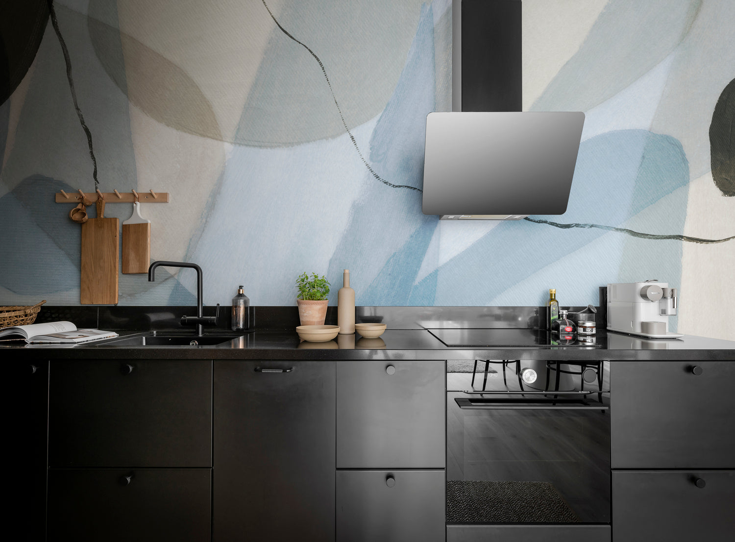 Asana, Abstract Mural Wallpaper in blue featured on the wall of a kitchen area with black cabinets
