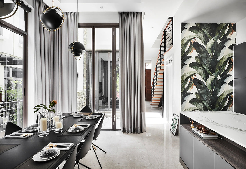 Banana Leaves, Tropical Pattern Wallpaper featured on a wall of dining area with black dining table and chairs with grey curtains and a black framed curtain wall