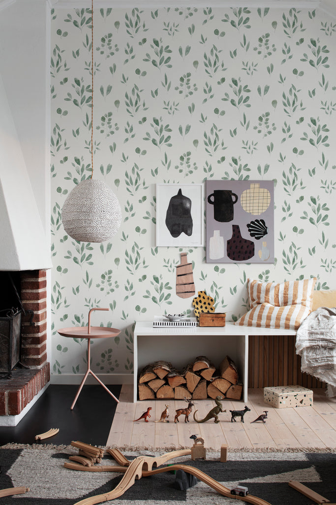 Belle Foliages, Tropical Pattern Wallpaper in Green Featured on a wall of a children’s playroom with several wooden toys scattered around