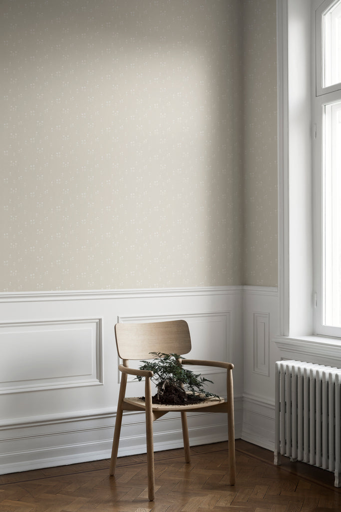 Bianca, Floral Pattern Wallpaper in Sand Featured on a wall of a room with a wooden chair next to a window