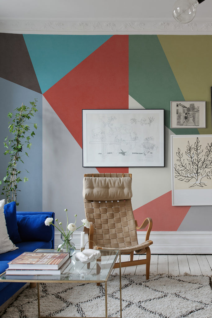 Big Summer Diamond, Mural Wallpaper featured on a wall of a living area with a round glass table, black sofa, and multicolored pillows, a round glass table 