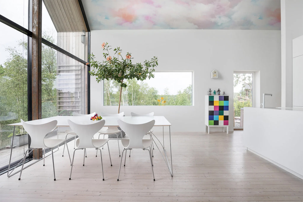 Bubble Gum Clouds, Pastel Mural Wallpaper featured on a ceiling of a modern house with wood flooring and white table and chairs. 