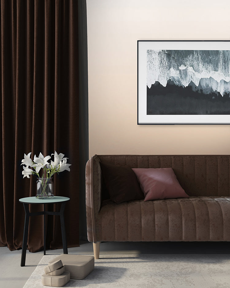 Modern room featuring Calbri Ombre Wallpaper, transitioning from beige at the base to a lighter hue at the top. Complemented by a dark brown velvet sofa, a green round table with white lilies, and abstract art.