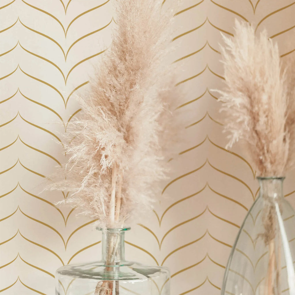 Elegant room with Chevron, Matte Gold Pattern Wallpaper. Foreground features two glass vases with beige pampas grass. The wallpaper provides a sophisticated backdrop, creating a mood of modern elegance.