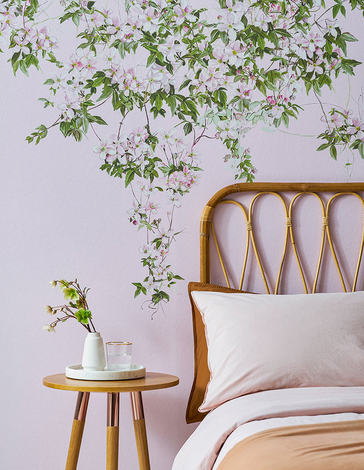 Cozy bedroom with Classic Clematis, Floral Mural Wallpaper in Pink. A wooden bed with white bedding and a side table with decor enhance the serene and elegant atmosphere.