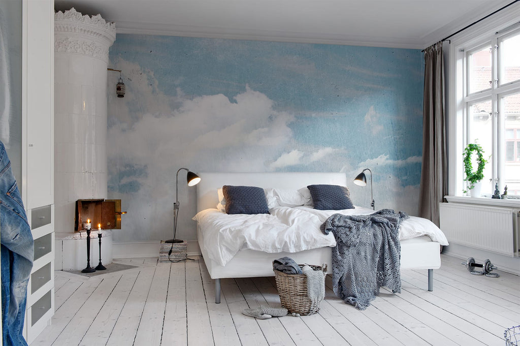 Clouds Above, Mural Wallpaper featured on a wall of a bedroom with a bed that has white sheets and grey throw blanket and pillows