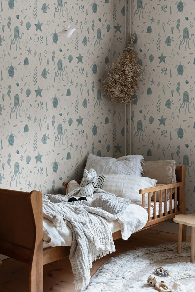 Corals and Friends, Wallpaper in Blue Featured on a wall of a kid’s room with a bed on a wooden frame with soft fabric and pillows