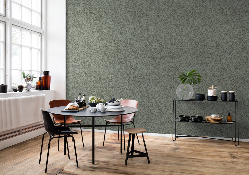 Crackle, Pattern Wallpaper in sage featured on a wall of a dining area with black round table and multicolored chairs