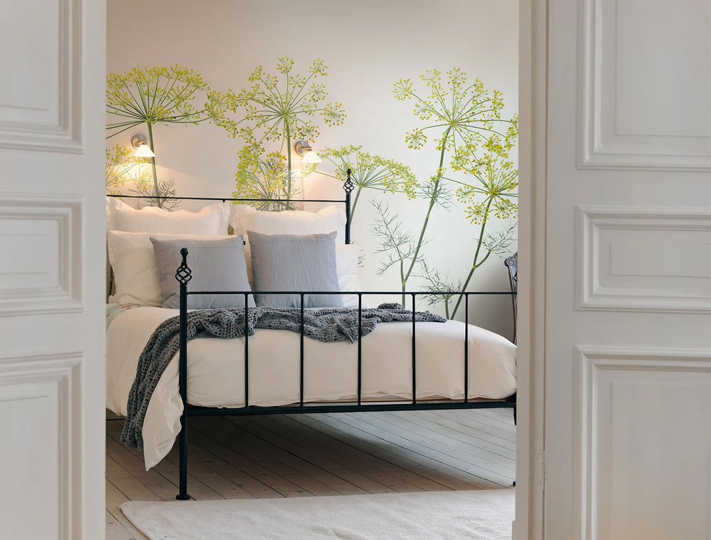 Crown of Dill, Mural Wallpaper featured on a wall of a bedroom with white bedsheets and grey throw blanket and pillow as seen from a door of its entrance