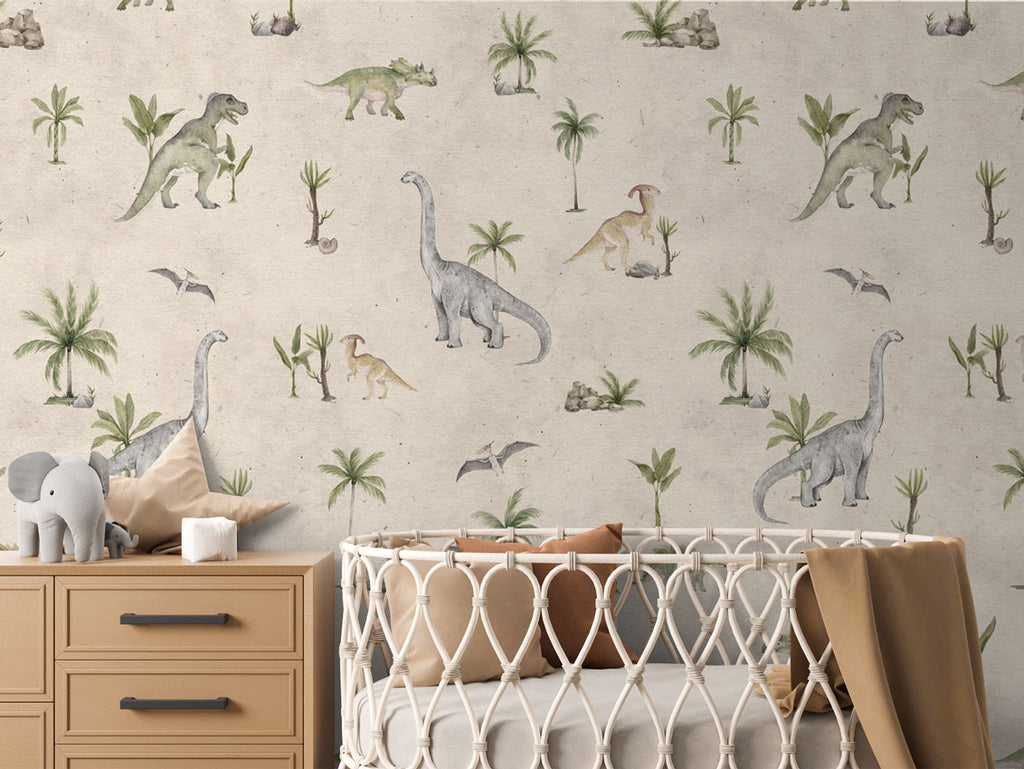 Dashing Dino, Pattern Wallpaper in sand colourway, featuring various dinosaurs and prehistoric plants. The nursery room includes a wooden dresser with an elephant plush toy, and a crib with a brown blanket.