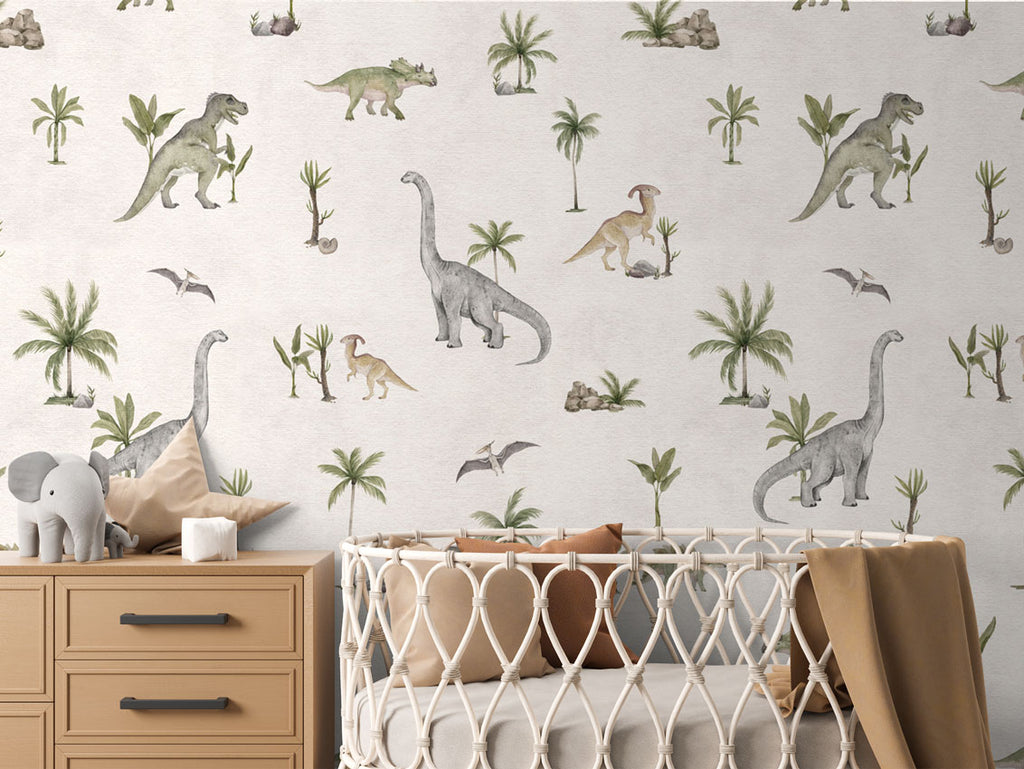 Dashing Dino, Pattern Wallpaper in white colourway, featuring various dinosaurs and prehistoric plants. The nursery room includes a wooden dresser with an elephant plush toy, and a crib with a brown blanket.