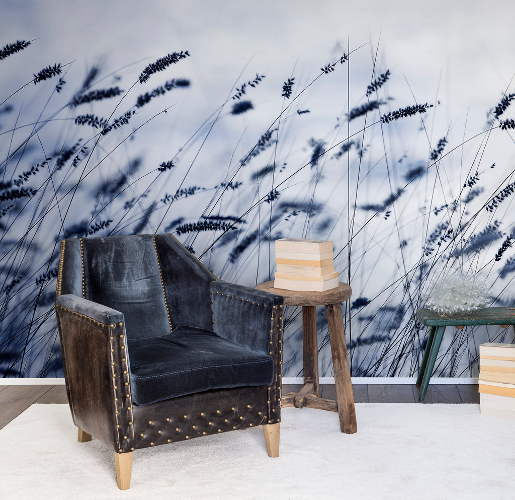 Dusk Breeze, Blue Landscape Wallpaper featured on a wall of a room with a vintage single sofa chair and wooden stool
