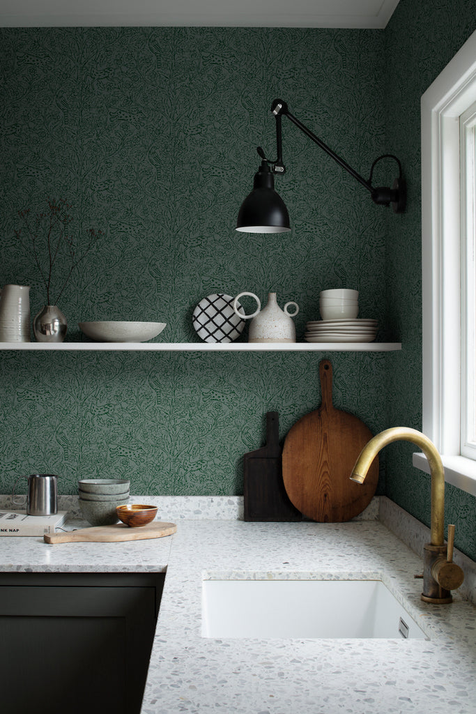 Eden and Friends, Wallpaper in Dark Green Featured on a wall of a kitchen with white granite countertop with several ceramic kitchenwares