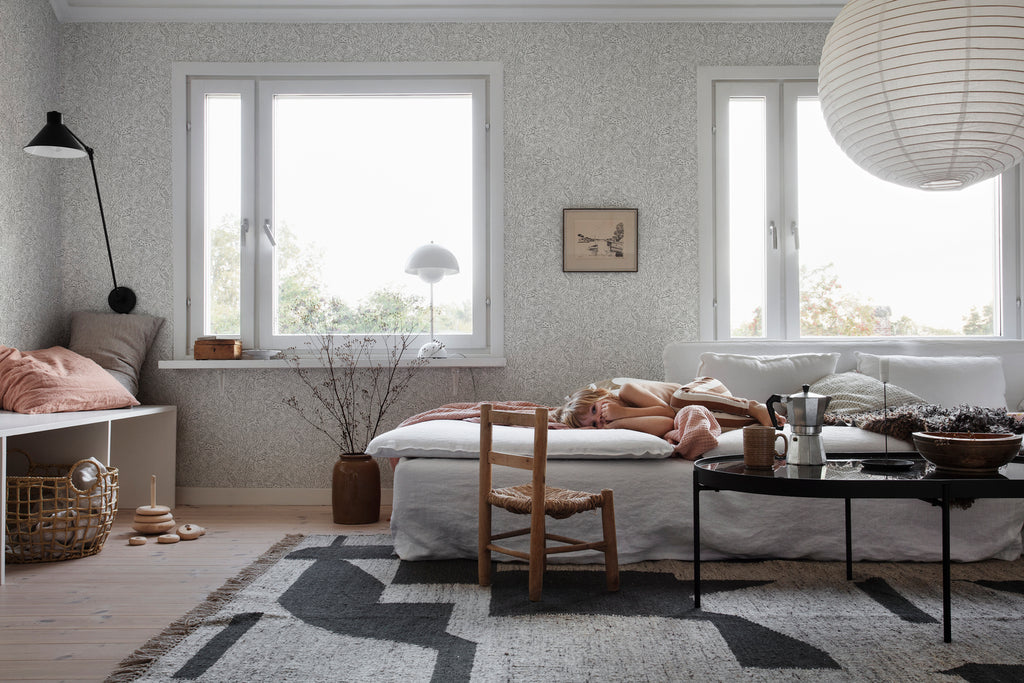 Eden and Friends, Wallpaper in Grey Featured on a wall of a bedroom with a patterned floor mat, and cozy atmosphere 