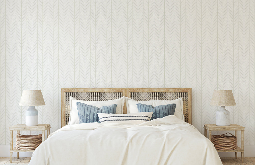 A well-lit, airy bedroom with a neatly made bed, flanked by wooden nightstands holding elegant lamps. The room exudes a warm and inviting ambiance, enhanced by the subtle Hand-Drawn Herringbone Pattern Wallpaper.