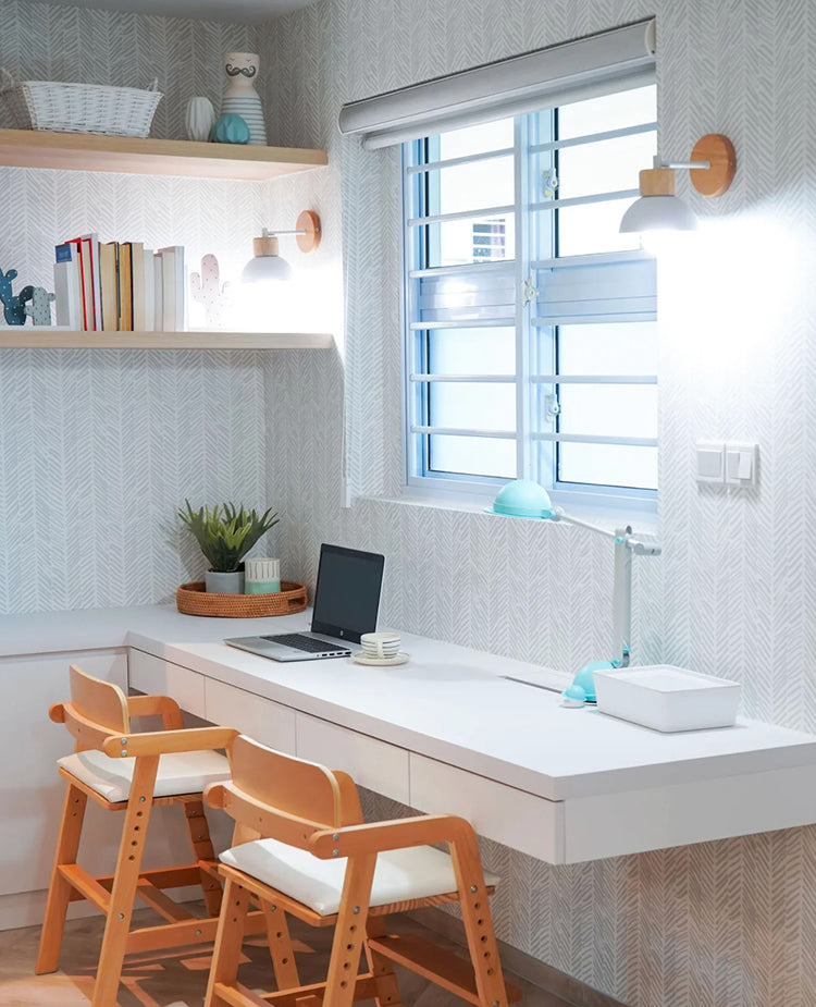 Modern workspace adorned with Herringbone by Sophie, Pattern Wallpaper, featuring a white desk, laptop, books, lamp, two orange chairs, and a potted plant on a windowsill.