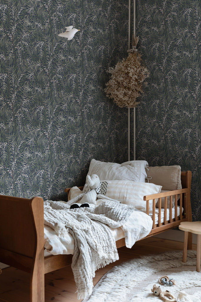 Idun, Nature Pattern Wallpaper in dark blue in a kid's room with a wooden bed with soft cushion and soft blankets, with a plush elephant toy. 