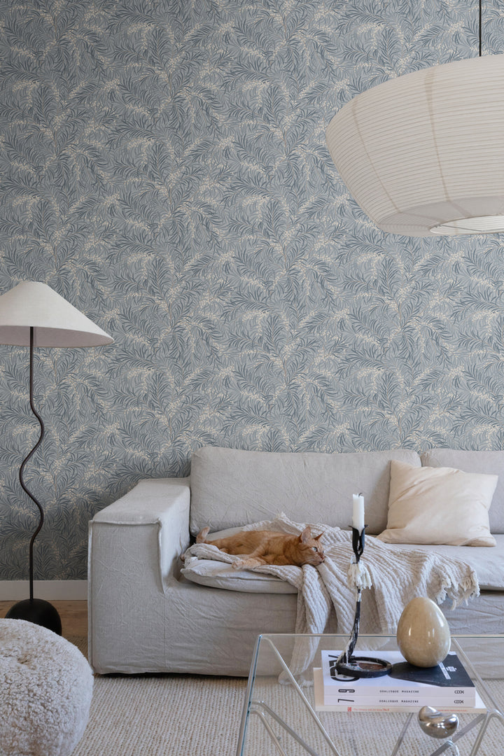 Idun, Nature Pattern Wallpaper in light blue featured on a wall of a bedroom with a bed with a patterned sheets and pillows.