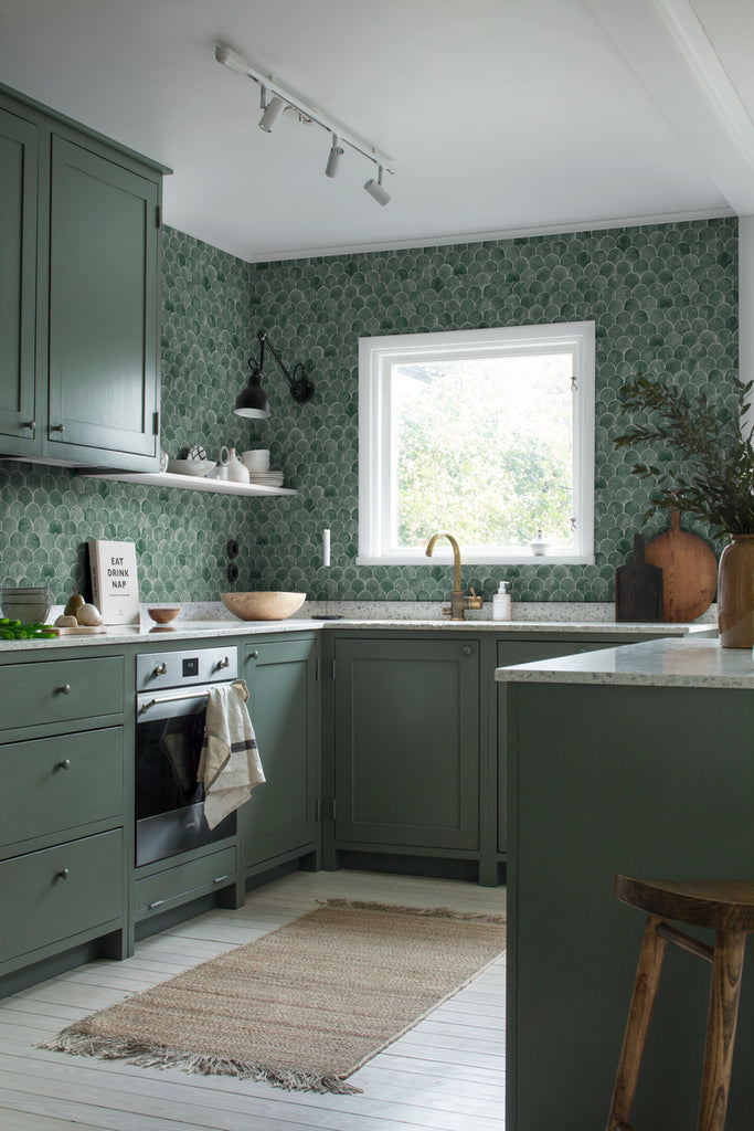 Igor Shells, Pattern Wallpaper in green featured on a wall of a kitchen area with green finish on the countertop cabinet and wooden flooring