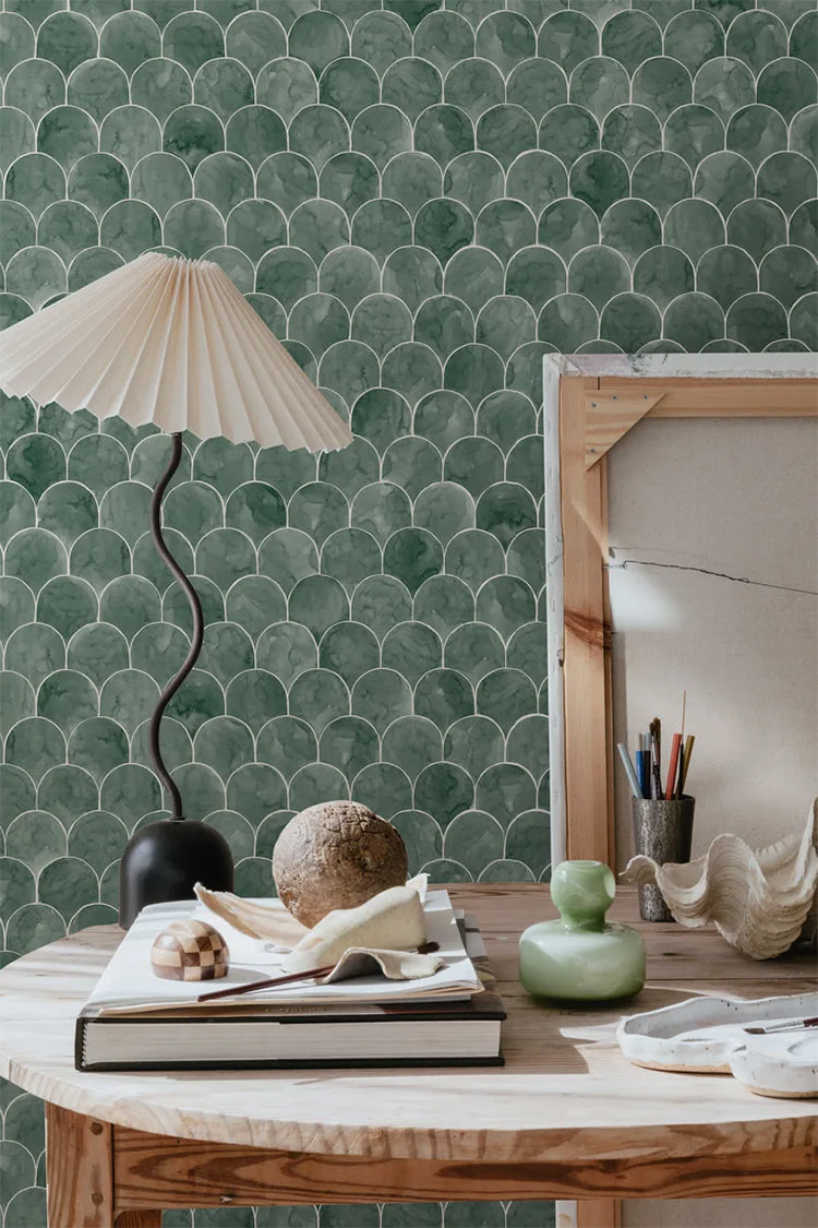 Igor Shells, Pattern Wallpaper in green featured on a wall of a room with a wooden round table with a lamp, books and furnitures 