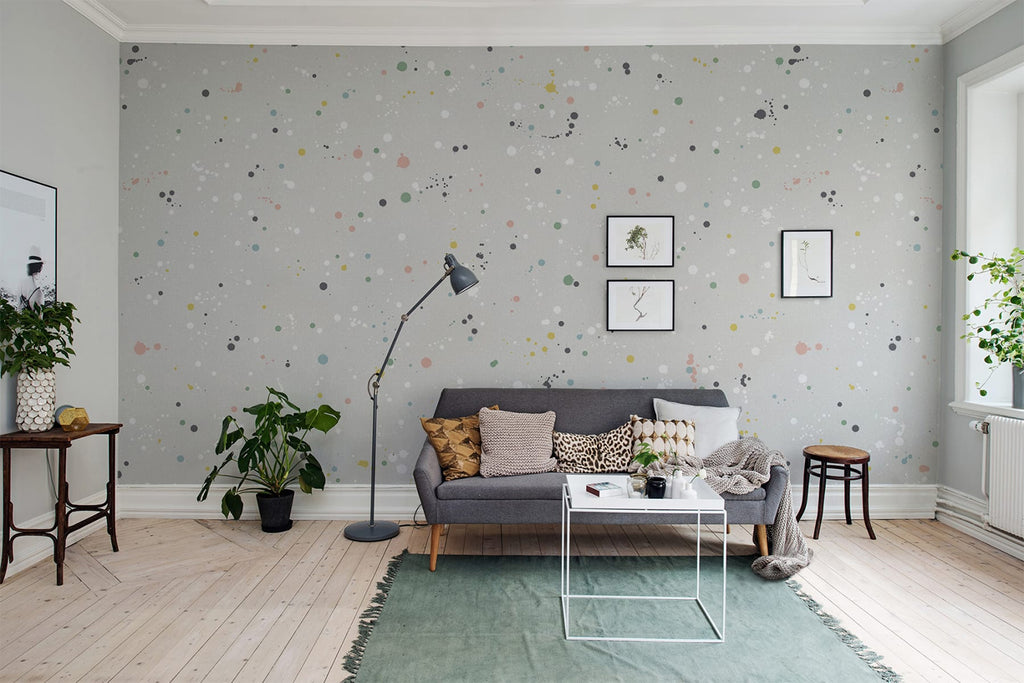 Inked!, Pattern Wallpaper in blush pink grey featured on a wall of a living area with grey sofa and multiple pillows, green floor mat and wooden floorings