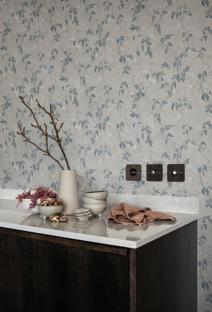 Irene, Floral Pattern Wallpaper in Blue featured on a wall a kitchen with a countertop with white marble finish on top are cloth, and ceramic kitchenwares.