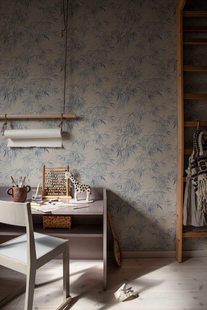 Jon Watercolor Bamboo Japanese Wallpaper in Blue Featured on a wall of a study room with wooden table, chair, ladder, and flooring